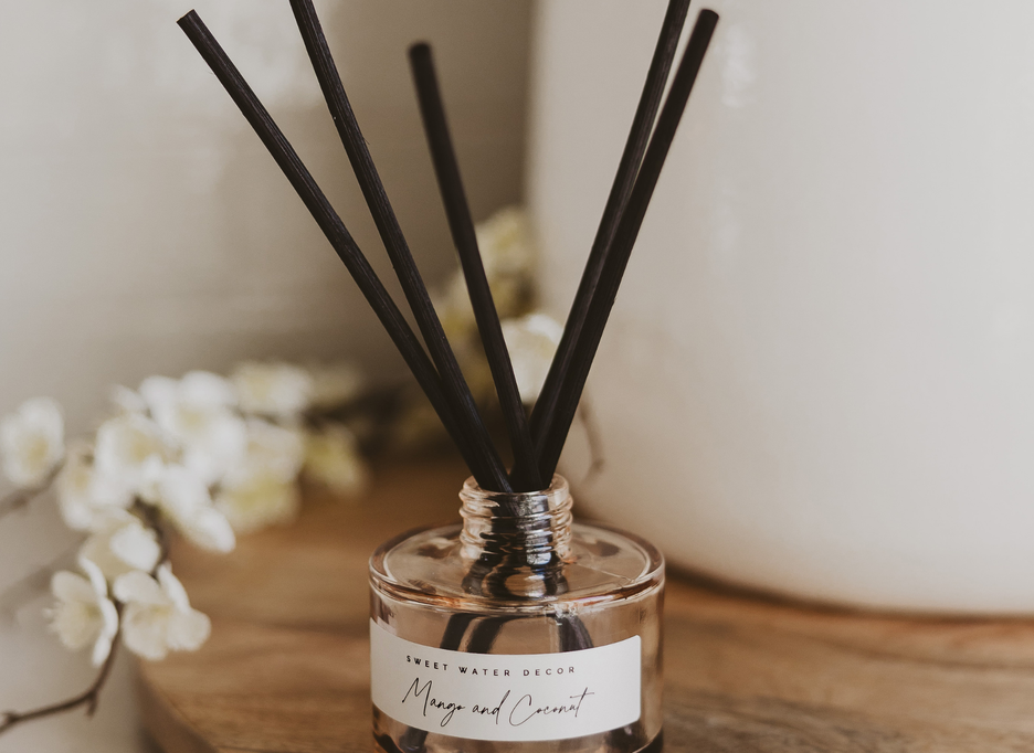 Mango and Coconut reed diffuser on a wooden tray with white flowers, bringing warmth and beauty to everyday living.
